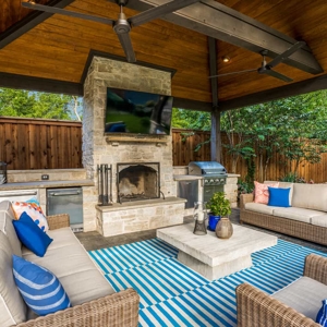 Covered patio with outdoor furniture and a fireplace with a mounted tv